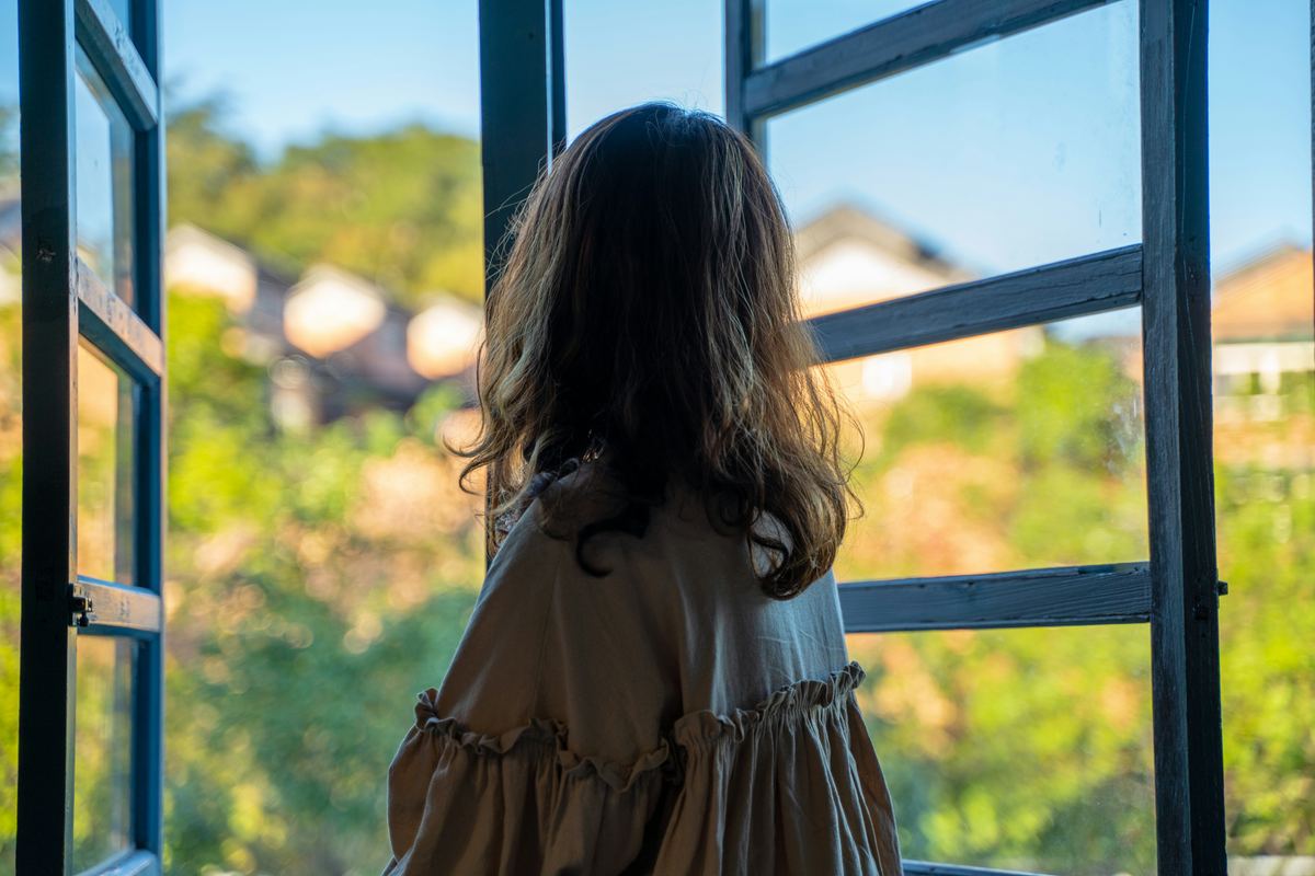 Frau schaut nachdenklich aus dem Fenster